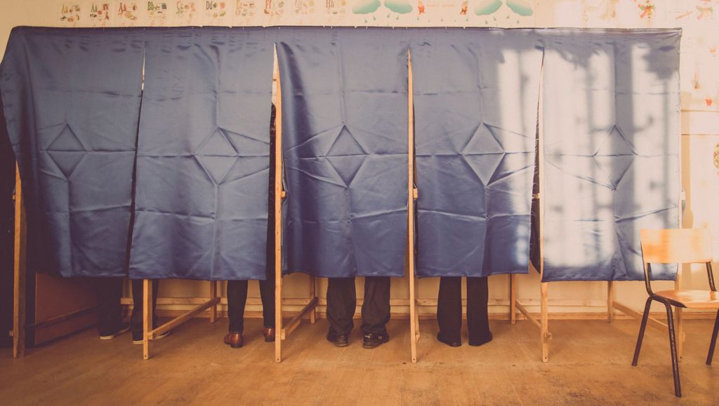 People at polling station voting behind curtain